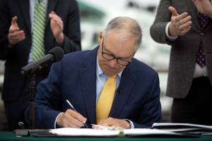 Governor Jay Inslee signs SB 5974 into law during a bill signing Friday, March 25, 2022, outside the ferry terminal in Mukilteo, Washington. (Ryan Berry / The Herald)