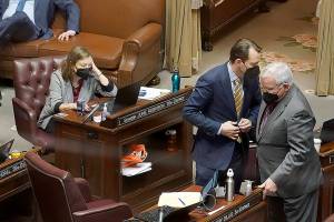 Sen. Andy Billig (D-Spokane), second from right, confers with Sen. Sam Hunt, D-Olympia, right, in front of Sen. June Robinson's, D-Everett, desk on the Senate floor at the Capitol in Olympia, Wash., on Tuesday, Feb. 15, 2022, during debate over a measure that authorizes legislative leaders to terminate any state of emergency called by the governor after 90 days if the Legislature is not in session. The measure passed the Democratic-led Senate chamber and now heads to the House, also held by Democrats, for consideration. (AP Photo/Ted S. Warren)