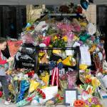 A young child brings flowers to the memorial of fallen Everett Police Officer Dan Rocha on Saturday in Everett. (Ryan Berry / The Herald)