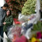 Two people look on in silence at the memorial for Everett Police Officer Dan Rocha a day after his death in the line of duty, Saturday in Everett. (Ryan Berry / The Herald)