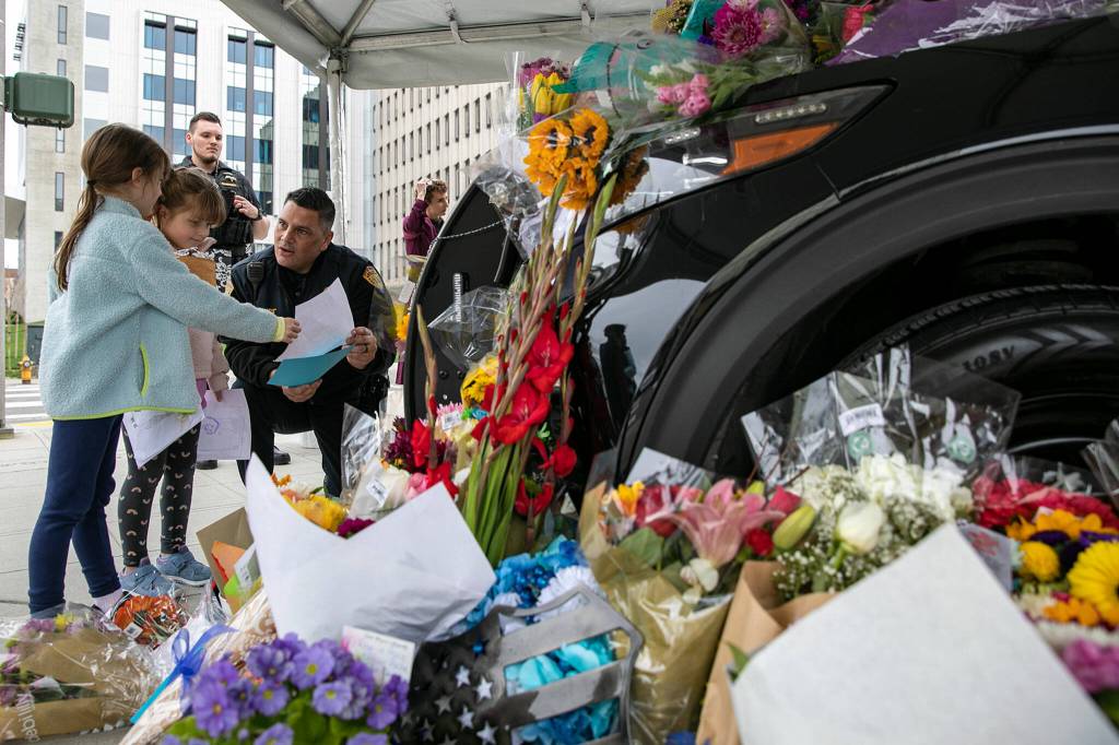 Everett Deputy Police Chief John DeRousse speaks with two young girls as they drop off drawings at the memorial for slain officer Dan Rocha on Saturday in Everett. (Ryan Berry / The Herald)