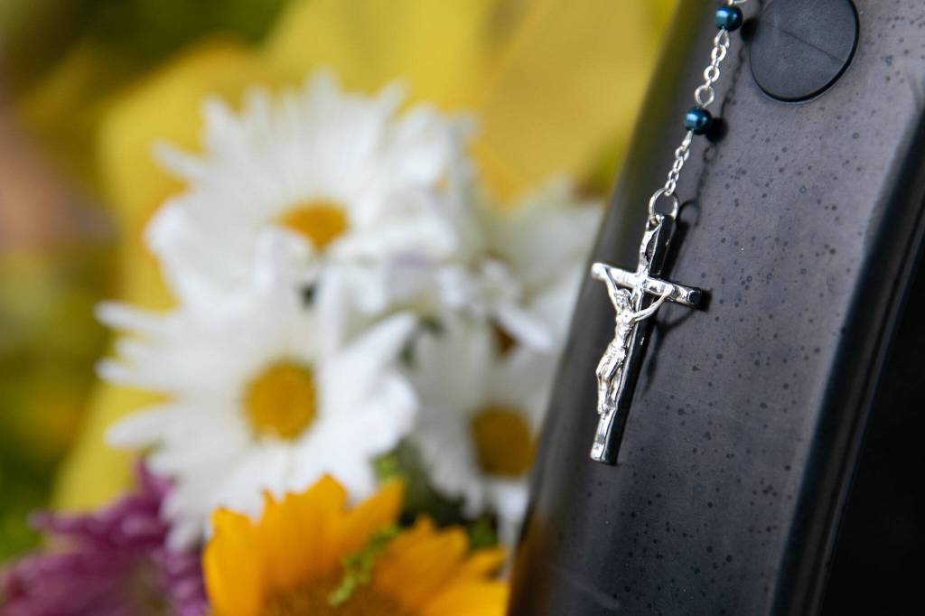 A small crucifix hangs from the bumper of a police vehicle at officer Dan Rochas memorial Saturday in Everett. (Ryan Berry / The Herald)