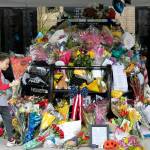 A young child brings flowers to the memorial of fallen Everett Police Officer Dan Rocha Saturday, March 26, 2022, in Everett, Washington. (Ryan Berry / The Herald)