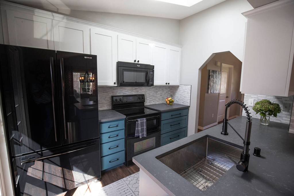 In Shelly Hendersons kitchen, the bottom cabinets were painted blue to add a pop of color, while the cherry upper cabinets were painted white. A gray quartz countertop is complemented by a gray and white tile backsplash. (Andy Bronson)