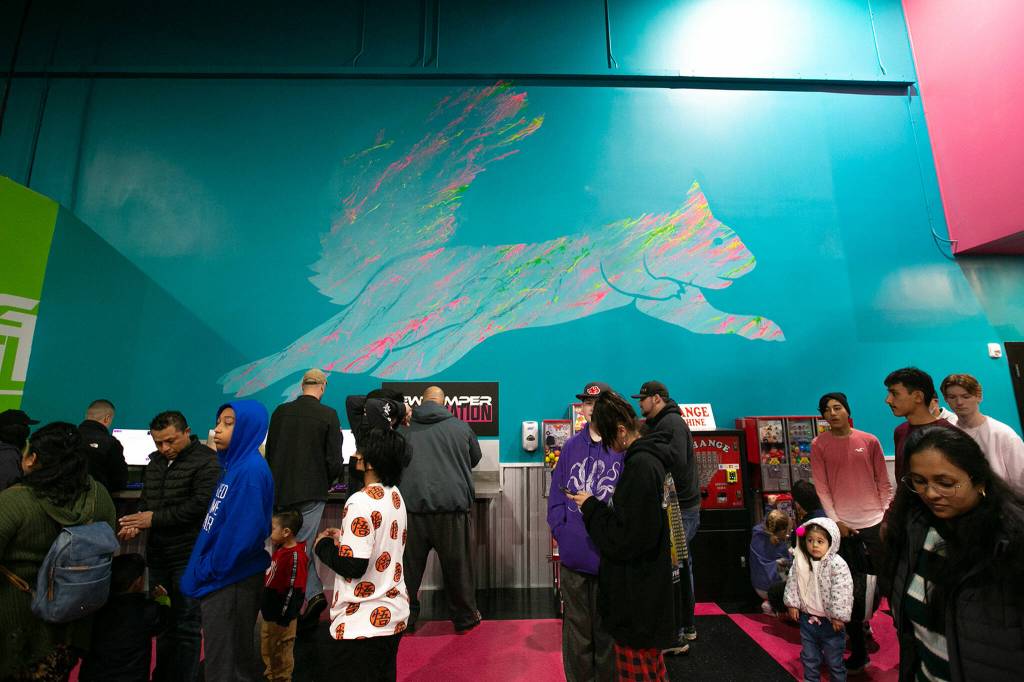 A squirrel logo is painted on the wall as people wait in line for their tickets at Flying Squirrel trampoline park. (Ryan Berry / The Herald)