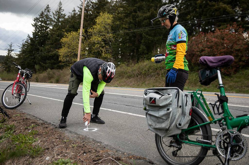 Steve Boskovich spray paints a Dan Henry directional mark along Highway 532 on Sunday, April 10, 2022 in Camano Island, Washington. (Olivia Vanni / The Herald)