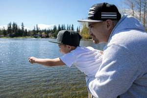 Randy Tharp and his 6-year-old son hang by the railing of a dock and count ducks at Lake Goodwin Community Park on Saturday, April 9, 2022, in Stanwood, Washington. (Ryan Berry / The Herald)