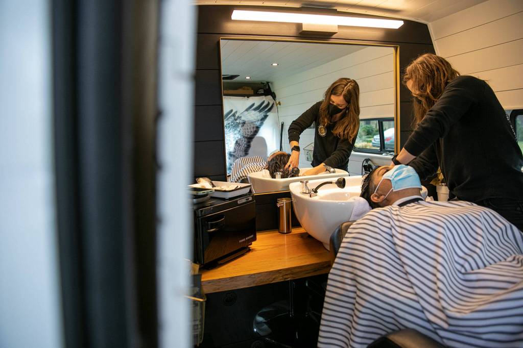 Stylist Alex Lewis washes Anna Kincaids hair before giving it a cut outside Kincaids home. (Ryan Berry / The Herald)