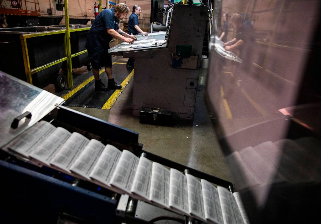 Mike Tullar and Alex Hanson examine Herald papers as they roll off the press in Everett. (Olivia Vanni / The Herald)