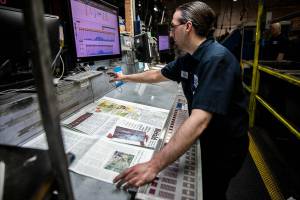 Alex Hanson looks over sections of the Herald and sets the ink on Wednesday, March 30, 2022 in Everett, Washington. (Olivia Vanni / The Herald)