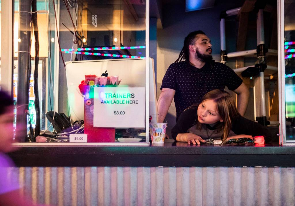 CJ Lewis and Alex Queen wait for the recipient of a secret admirer rose to come to the booth to claim it on Sunday at the Everett Skate Deck. (Olivia Vanni / The Herald)