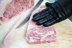 Sean Sanderson trims excess fat off a New York cut of Wagyu at EC Wilson Meats on Tuesday, March 29, 2022 in Lynnwood, Washington. (Olivia Vanni / The Herald)