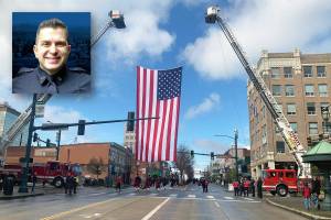 An American flag was hung over the passing motorcade honoring slain Everett police officer Dan Rocha on Monday in downtown Everett. (Jake Goldstein-Street / The Herald) 20220404
