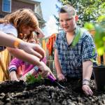 JR Stalkfleet digs out a hole for a tomato plant with his hand in the new outdoor classroom at Tomorrow’s Hope Child Development Center on Friday, April 22, 2022 in Everett, Washington. (Olivia Vanni / The Herald)