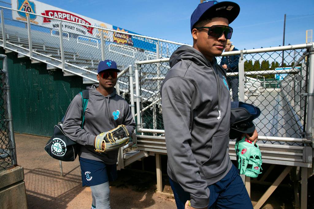 Mariners prospects Noelvi Marte, right, and Alberto Rodriguez enter the field together during an AquaSox team workout Wednesday, April 6, 2022, at Funko Field in Everett, Washington. (Ryan Berry / The Herald)