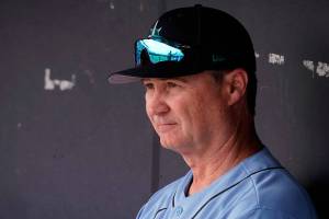 Seattle Mariners manager Scott Servais watches from the dugout before a spring training baseball game against the Texas Rangers Monday, March 28, 2022, in Peoria, Ariz. (AP Photo/Charlie Riedel)