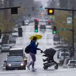 A woman quickly crosses Hoyt Avenue while pushing a stroller as it starts to rain heavily on March 30 in Everett. (Olivia Vanni / The Herald)