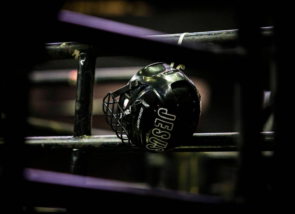 A bull riding helmet with the word JESUS hangs on a railing during the PBR Everett Invitational at Angel of the Winds Arena on Wednesday, April 6, 2022 in Everett, Washington. (Olivia Vanni / The Herald)