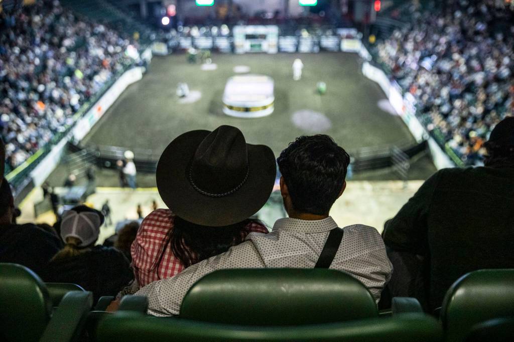 A couple watches the PBR Everett Invitational at Angel of the Winds Arena on Wednesday, April 6, 2022 in Everett, Washington. (Olivia Vanni / The Herald)