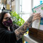 Lei Wiley-Mydske, co-owner of Stanwood Tattoo Company, thumbs through a collection of informational material she has at the autism acceptance library. (Ryan Berry / The Herald)