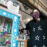 Lei Wiley-Mydske, co-owner of Stanwood Tattoo Company, stands with the Autism Acceptance Library that is installed at her shop on Friday, March 25, 2022, in Stanwood, Washington. (Ryan Berry / The Herald)