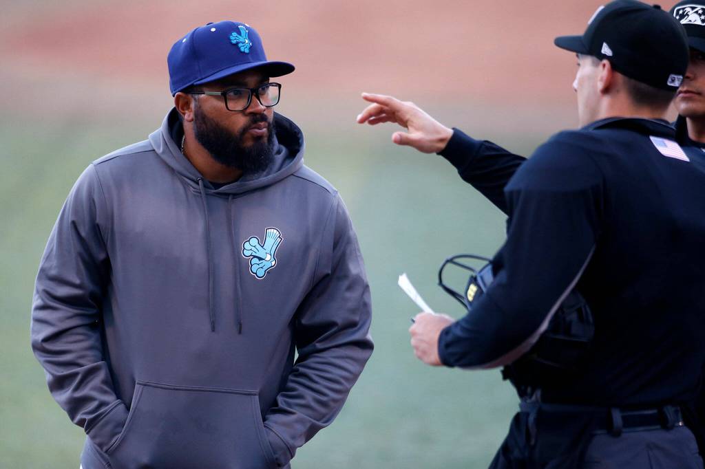 AquaSox manager Eric Farris talks with the umpires before a game against Eugene Friday, April 8, 2022, at Funko Field in Everett, Washington. (Ryan Berry / The Herald)