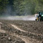 Andrew Albert drives his tractor and spreads fertilizer Friday across a field owned by the city of Arlington. (Ryan Berry / The Herald)