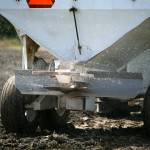 Fertilizer is thrown from a spreader Friday as Andrew Albert drives his tractor through a city-owned field in Arlington. (Ryan Berry / The Herald)