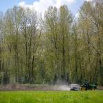 Andrew Albert fertilizes a field owned by the city of Arlington on Friday. (Ryan Berry / The Herald)