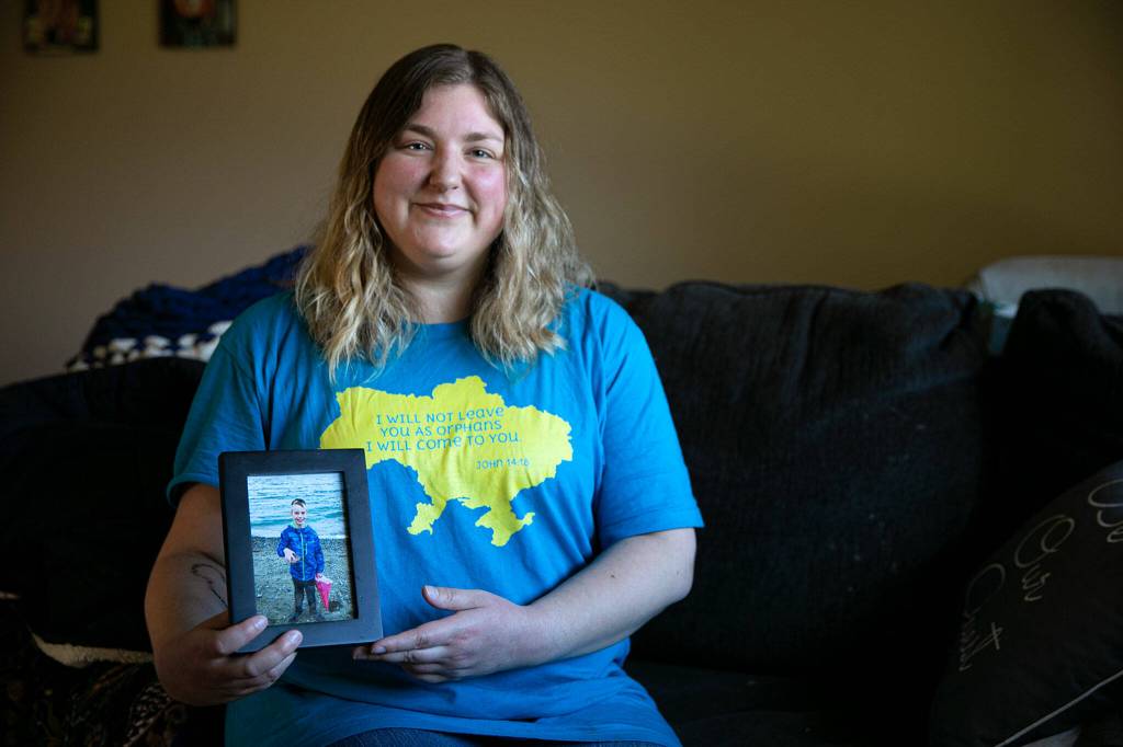 Katie-Jo Page sits in her living room with a photo of Mykyta on March 6 in Snohomish. (Ryan Berry / The Herald)