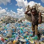 A man walks on a mountain of plastic bottles as he carries a sack of them to be sold for recycling after weighing them at the dump in the Dandora slum of Nairobi, Kenya on Dec. 5, 2018. (Ben Curtis / Associated Press file photo)