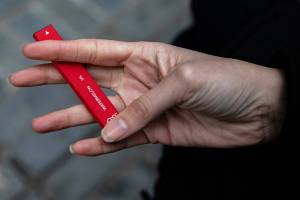 FILE - In this Jan. 31, 2020 photo a woman holds a Puff Bar flavored disposable vape device in New York. The Food and Drug Administration says it will soon begin cracking down on vaping companies that have used a now-closed loophole to escape federal oversight, including the company behind a line of fruit-flavored e-cigarettes that have become the top choice among teenagers.  Under a new law taking effect Thursday, April 14, 2022, the FDA can regulate e-cigarettes and similar products that use synthetic nicotine. (AP Photo/Marshall Ritzel)