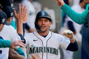 Seattle Mariners' Adam Frazier is greeted in the dugout after he scored on a single by Jesse Winker during the first inning of the team's baseball game against the Houston Astros, Friday, April 15, 2022, in Seattle. (AP Photo/Ted S. Warren)