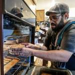 Charles Gill loads a cannabis-infused sweet potato cheesecake into the oven at his home in Everett, Washington. (Kevin Clark / The Herald)