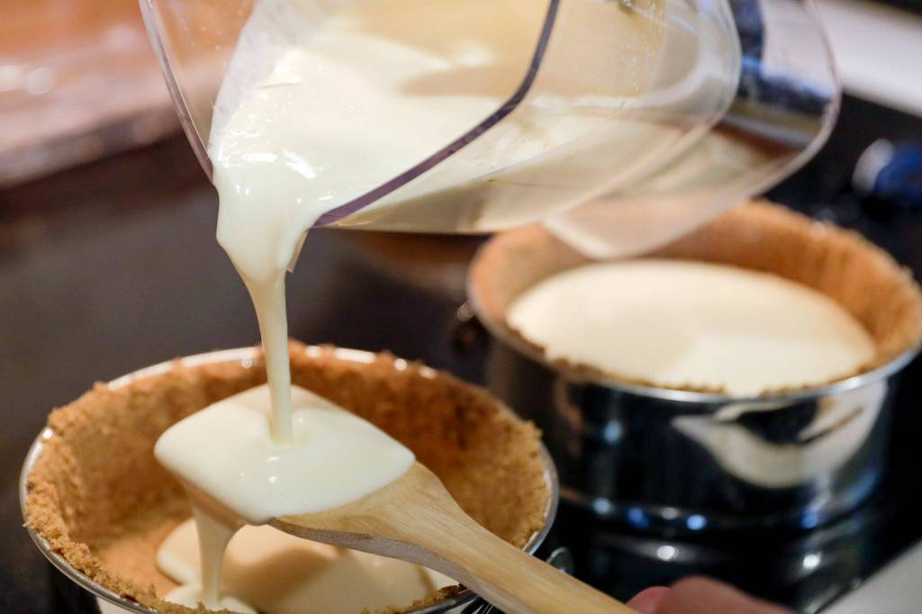 Charles Gill III pours a mix cannabis-infused cheesecake batter into a pan. (Kevin Clark / The Herald)