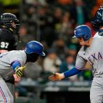 Texas Rangers' Nick Solak, right, is greeted by Adolis Garcia after Solak hit a two-run home run to score Garcia during the fifth inning against the Seattle Mariners in a baseball game Thursday, April 21, 2022, in Seattle. (AP Photo/Ted S. Warren)