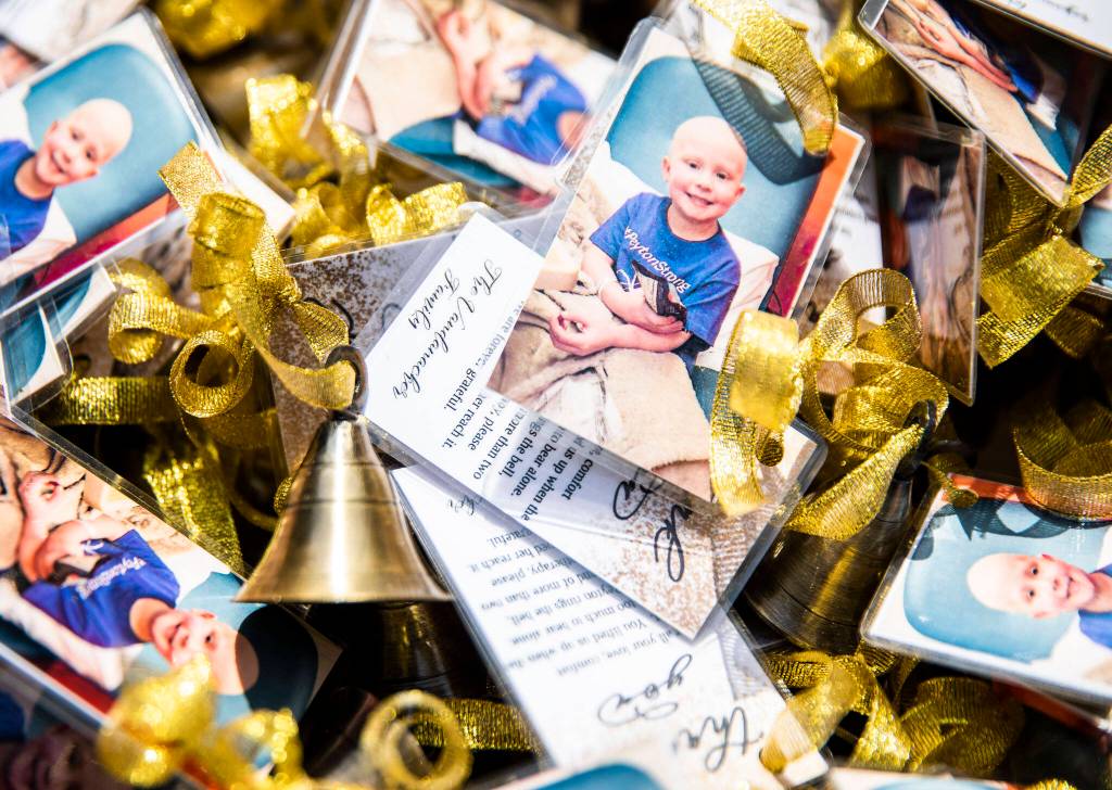 Small golden bells with thank you notes attached sit on a table for friend and family to grab to join Peyton in the ringing of her end of chemotherapy bell on Saturday, April 23, 2022 in Bothell, Washington. (Olivia Vanni / The Herald)