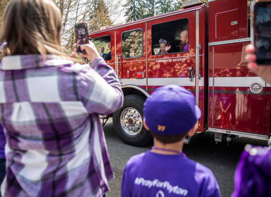 Peyton Vandanacker waves from a firetruck to friends and family gathered at her home to celebrate the end of her chemotherapy treatment on Saturday, April 23, 2022 in Bothell, Washington. (Olivia Vanni / The Herald)