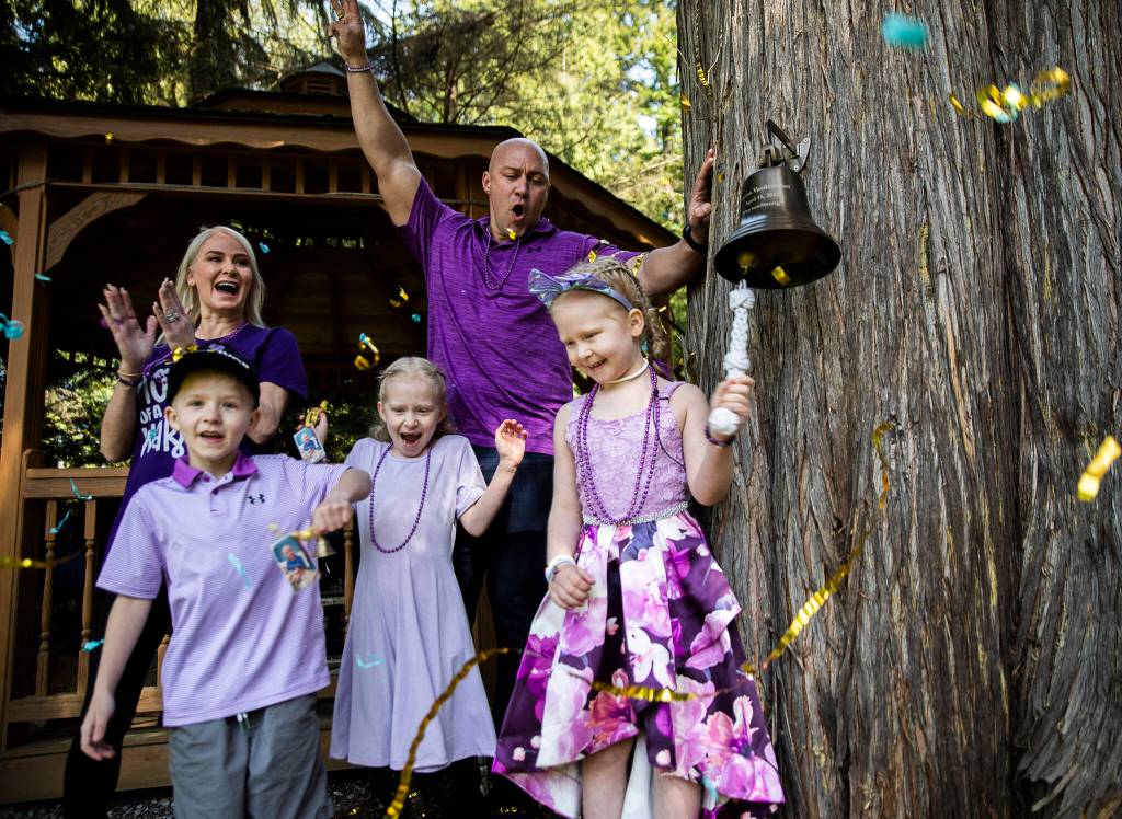 Photos by Olivia Vanni / The Herald 
Peyton Vandanacker, 7, rings her bell Saturday surrounded by her family in celebration of the end of her chemotherapy treatment for an aggressive type of leukemia. Top, Vandanacker waves from a fire truck to friends and family gathered at her home in Bothell.