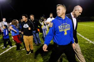 FILE - Bremerton High assistant football coach Joe Kennedy, front, walks off the field with his lawyer, right, Oct. 16, 2015, after praying at the 50-yard line following a football game in Bremerton, Wash. After losing his coaching job for refusing to stop kneeling in prayer with players and spectators on the field immediately after football games, Kennedy will take his arguments before the U.S. Supreme Court on Monday, April 25, 2022, saying the Bremerton School District violated his First Amendment rights by refusing to let him continue praying at midfield after games. (Lindsey Wasson/The Seattle Times via AP, File)