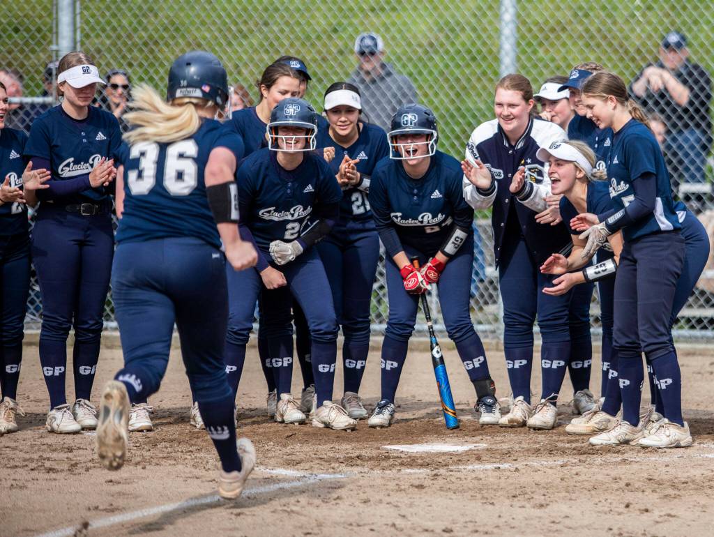 Glacier Peak players gather around home plate to congratulate teammate Bree Titus on hitting home run during the game against Jackson on Thursday, April 28, 2022 in Everett, Washington. (Olivia Vanni / The Herald)