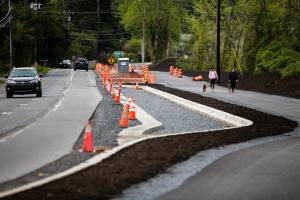 Traffic moves along Filbert Drive next to pedestrians walking along a new section of the North Creek Regional Trail on Friday, April 29, 2022 in Bothell, Washington. (Olivia Vanni / The Herald)
