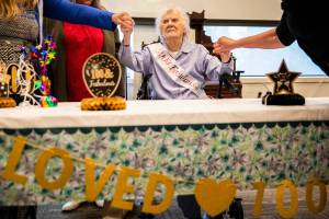 Ferne Violet Berg Ullestad holds hands of her family members while she sits are her table during her 100 year birthday celebration on Saturday, April 30, 2022 in Marysville, Washington. (Olivia Vanni / The Herald)
