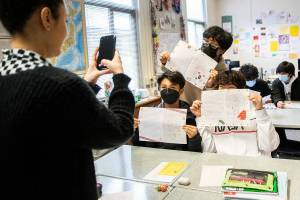 Japanese teacher Alicia Ceban takes a photo go her students Justin Mitosis, left, Christopher Araiza and Ethan Kwon with their pen pal letter they received from high school students in Japan at Mariner High School on Thursday, April 28, 2022 in Everett, Washington. (Olivia Vanni / The Herald)
