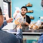 Wares Stanikzy hands a customer his bread at Alidas Bakery. (Olivia Vanni / The Herald)