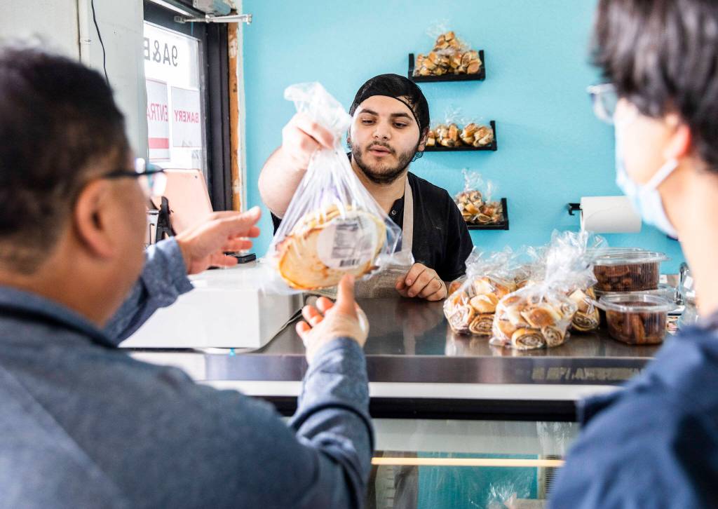 Wares Stanikzy hands a customer his bread at Alidas Bakery. (Olivia Vanni / The Herald)