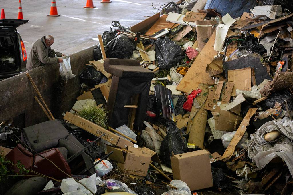 A man empties his trash into the massive pile of garbage Friday, April 29, 2022, at the Airport Road Recycling and Transfer Station in Everett, Washington. Due to the size of the garbage pile, there is less space for the public to offload their garbage, which is leading to longer wait times. (Ryan Berry / The Herald)