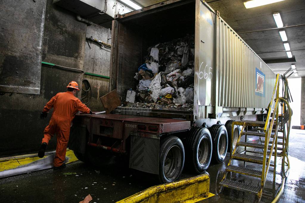 A worker prepares a truckload of trash for transport Friday, April 29, 2022, at the Airport Road Recycling and Transfer Station in Everett, Washington. The facility can send out around 40 of these containers each day. (Ryan Berry / The Herald)