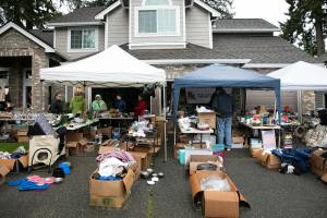 People look around at the non-profit group Church of Pugճ garage sale during the semi-annual Mill Creek community garage sale Saturday, May 7, 2022, in Mill Creek, Washington. Many people braved the heavy rain to venture from sale to sale. (Ryan Berry / The Herald)