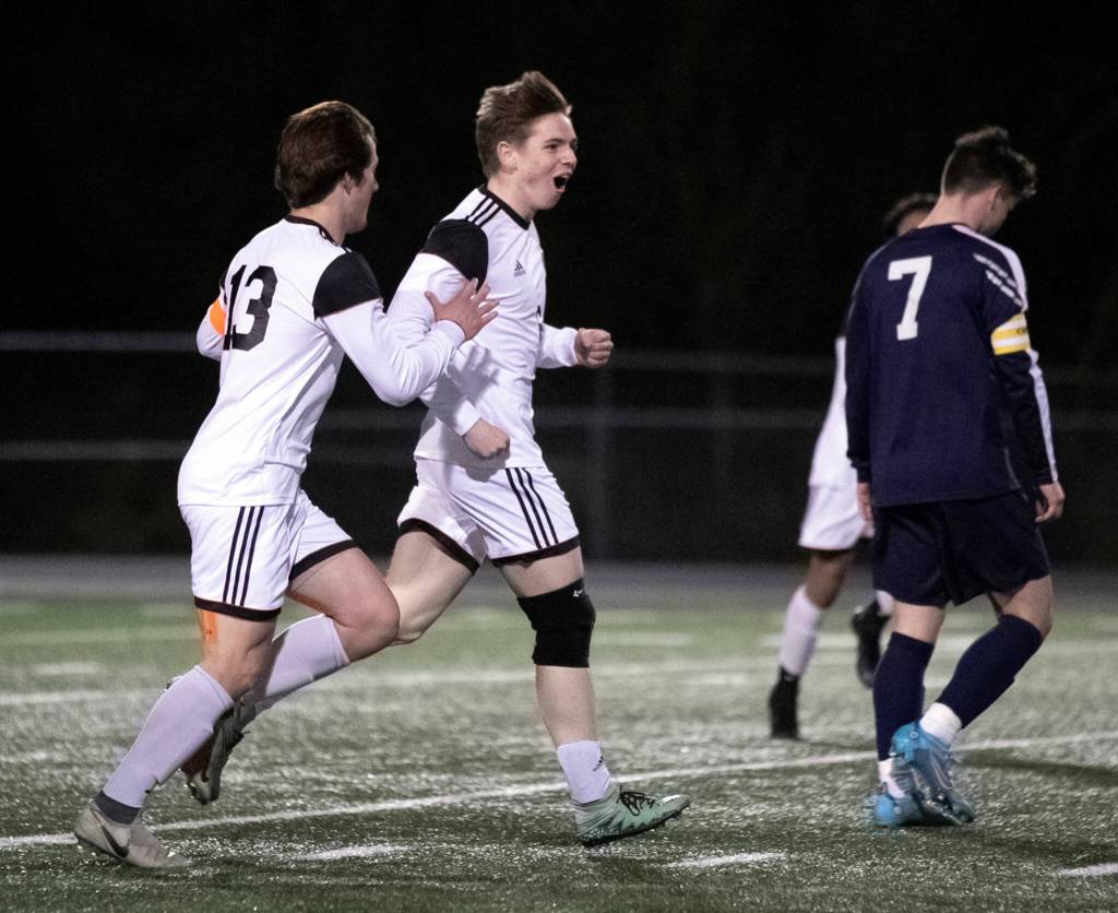 Monroes Alexis Pacheco-Alonso (center) celebrates a goal with teammate Joshua Gunter (left) during a game March 18 in Arlington. (Kevin Clark / The Herald)